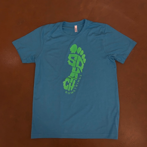 Squatch Branded Light Blue Tshirt on table